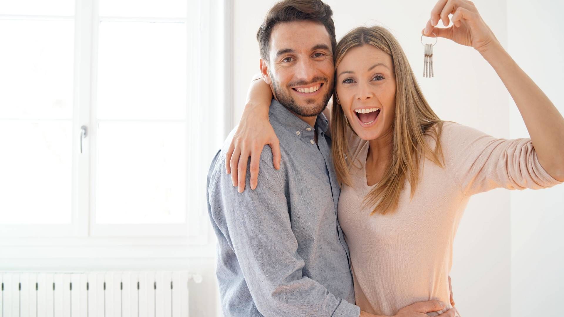 Happy new couple holding keys to a house they just bought near Lexington, KY