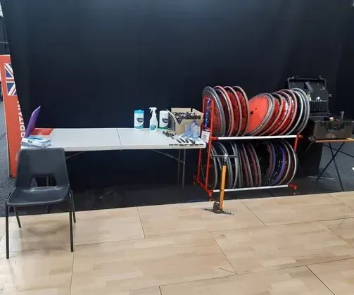 En reparationsstation med cykelhjul, værktøj og forsyninger på et bord mod en sort baggrund.