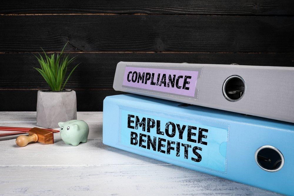 Employee Benefits and Compliance Binders on a desk