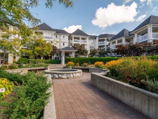 Courtyard garden with brick walkway, fountain, flowers, and apartment buildings under a blue sky
