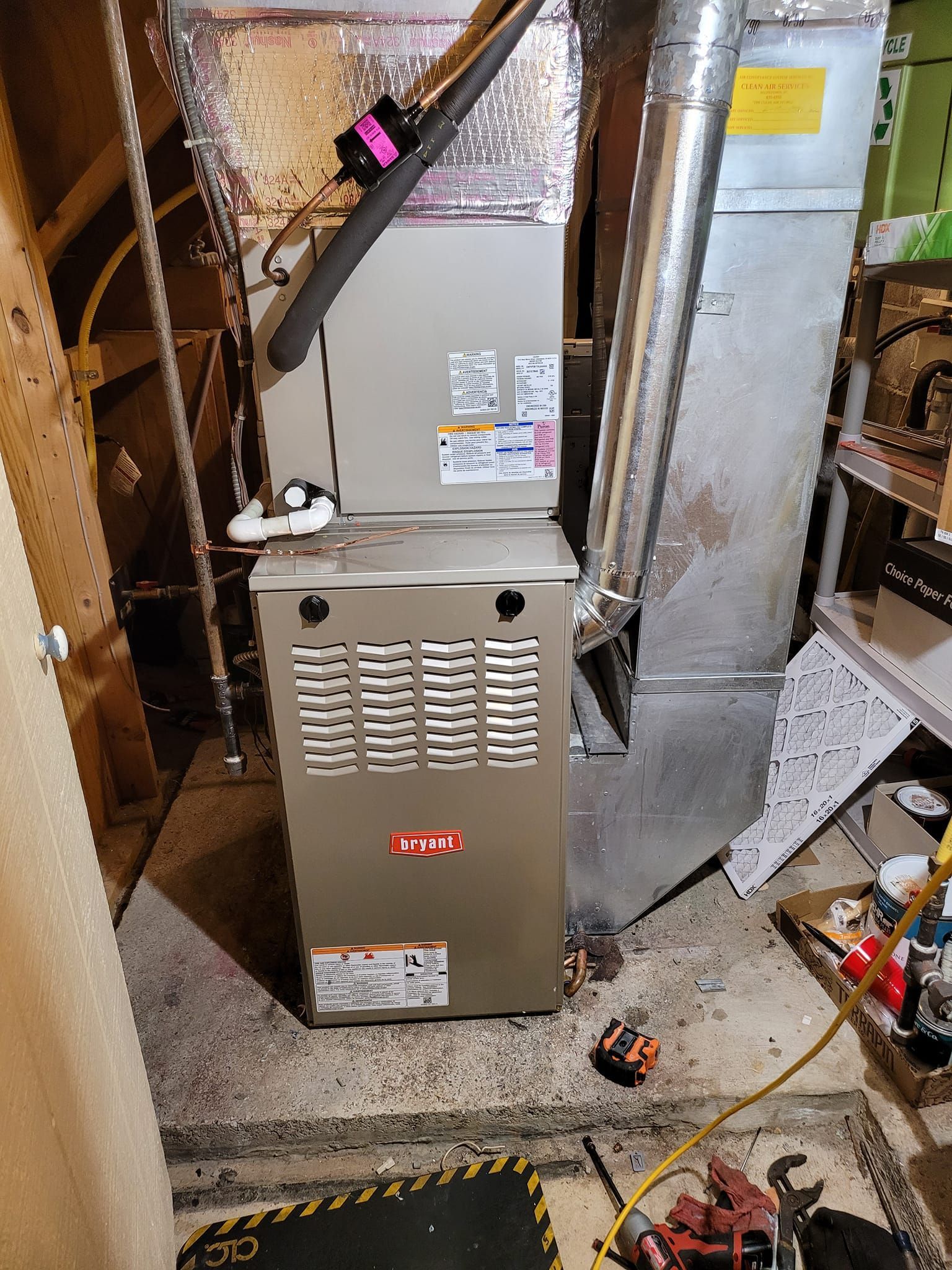 A furnace is sitting in a basement next to a staircase.