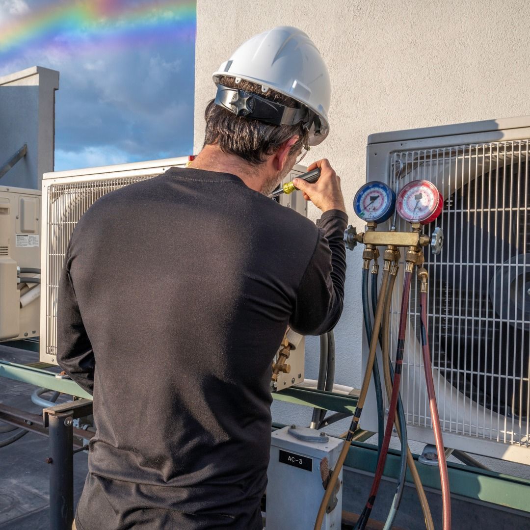 A man wearing a hard hat is working on an air conditioner