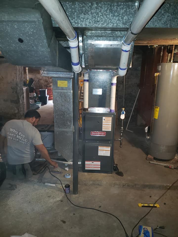 A man is working on a heating system in a basement.