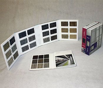 Carpet sample books open on a white surface, displaying various fabric swatches and a catalog.