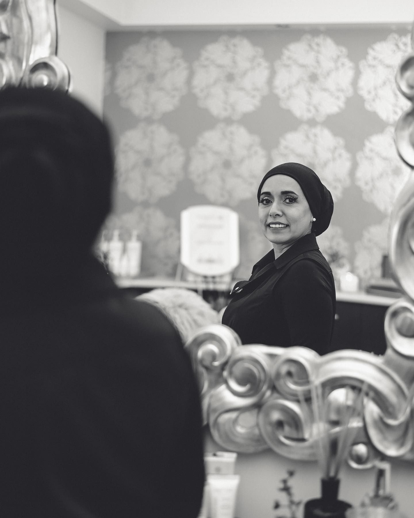 A woman is looking at her reflection in a mirror.