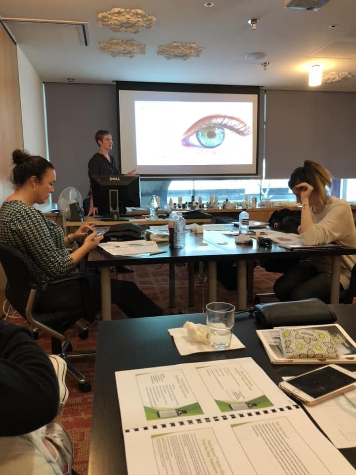 A woman is giving a presentation in front of a projector screen with an eye on it