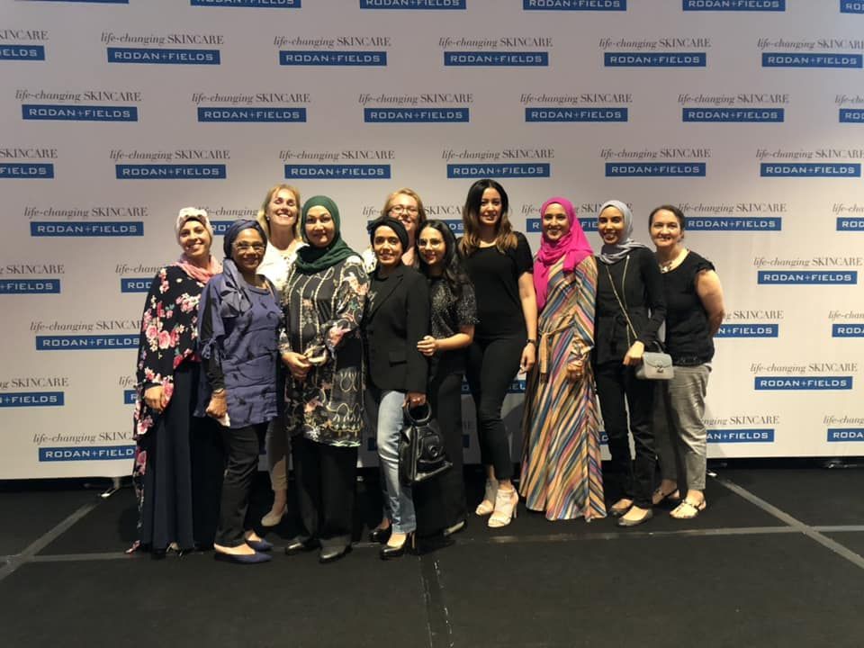 A group of women are posing for a picture in front of a wall.
