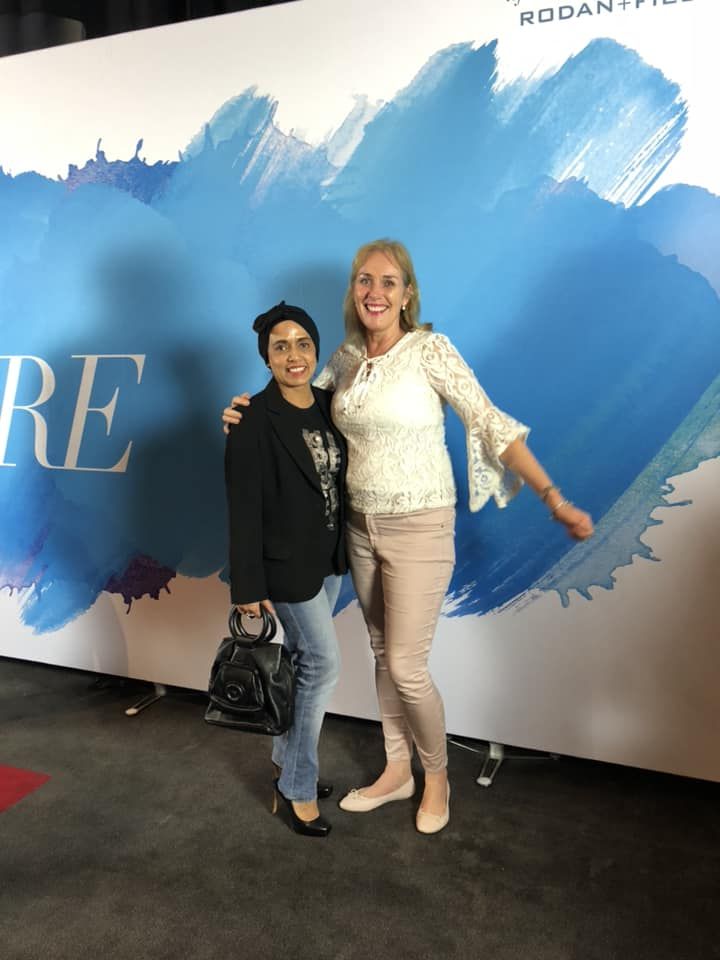 Two women standing in front of a sign that says re