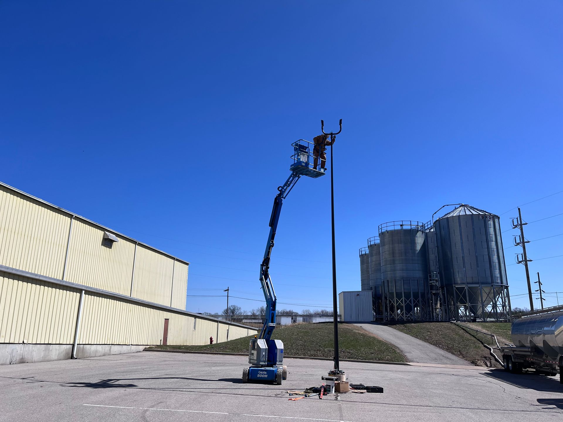 A man is working on a pole with a crane in a parking lot.