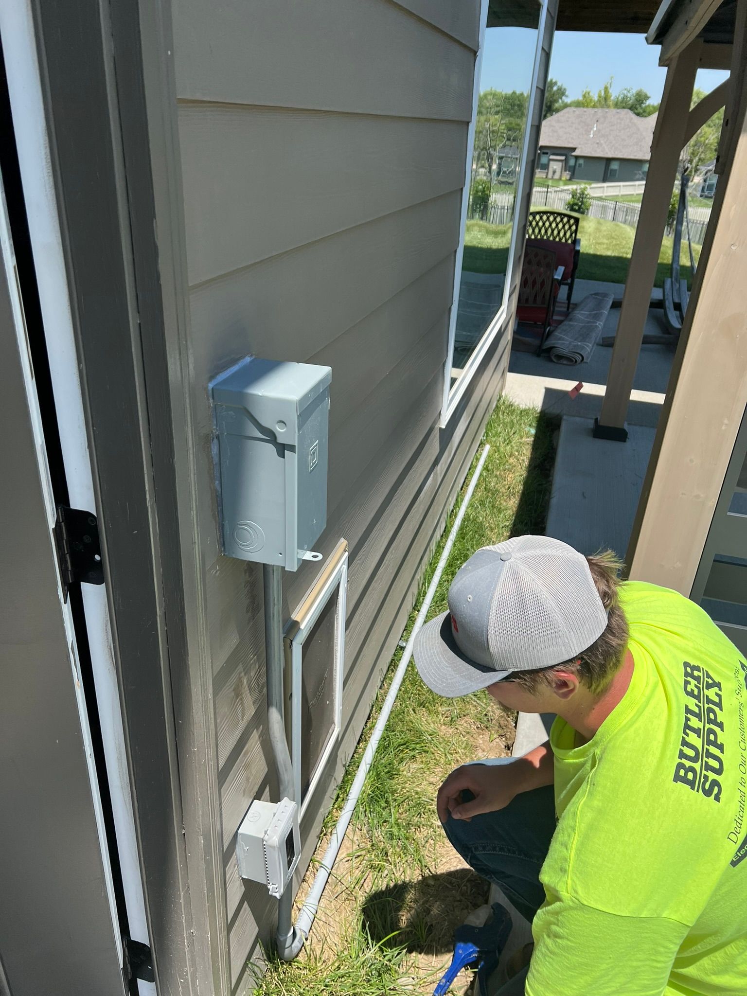 A man in a yellow shirt is working on the side of a house.