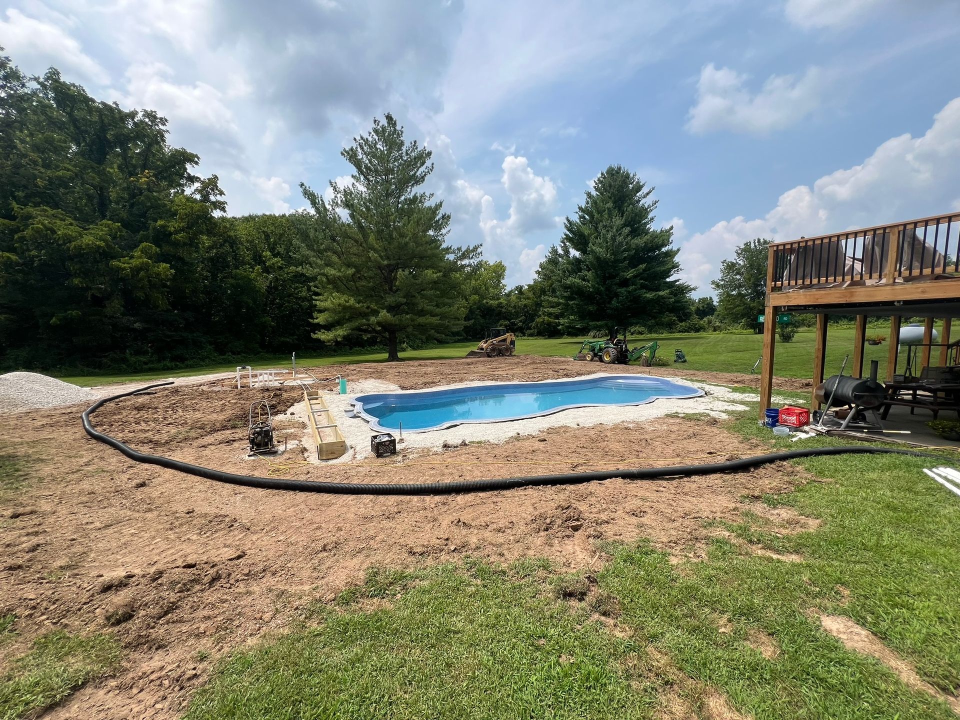 A large swimming pool is being built in the backyard of a house.