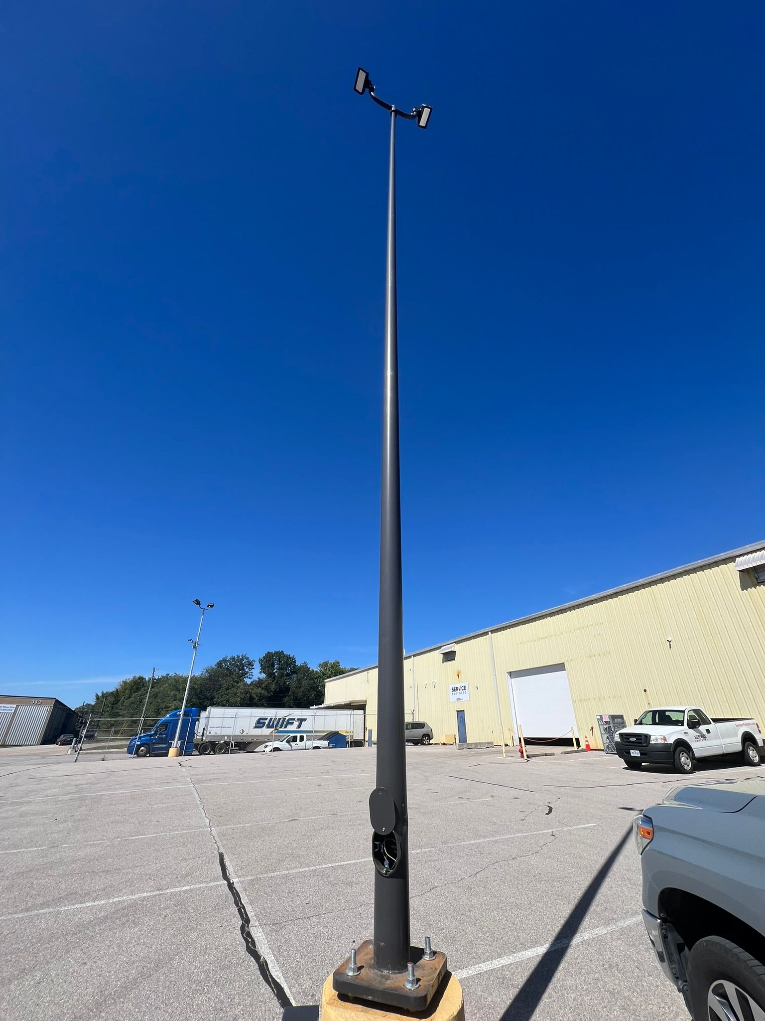 A street light is sitting in a parking lot in front of a building.