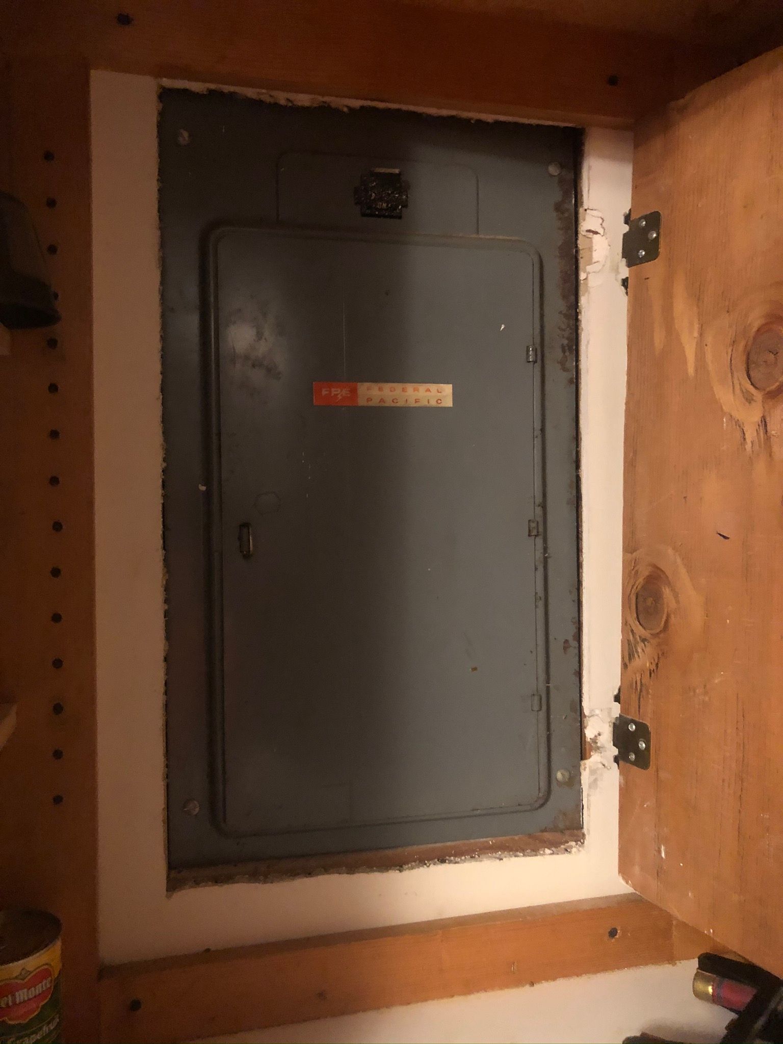 A electrical box is sitting inside of a wooden cabinet.