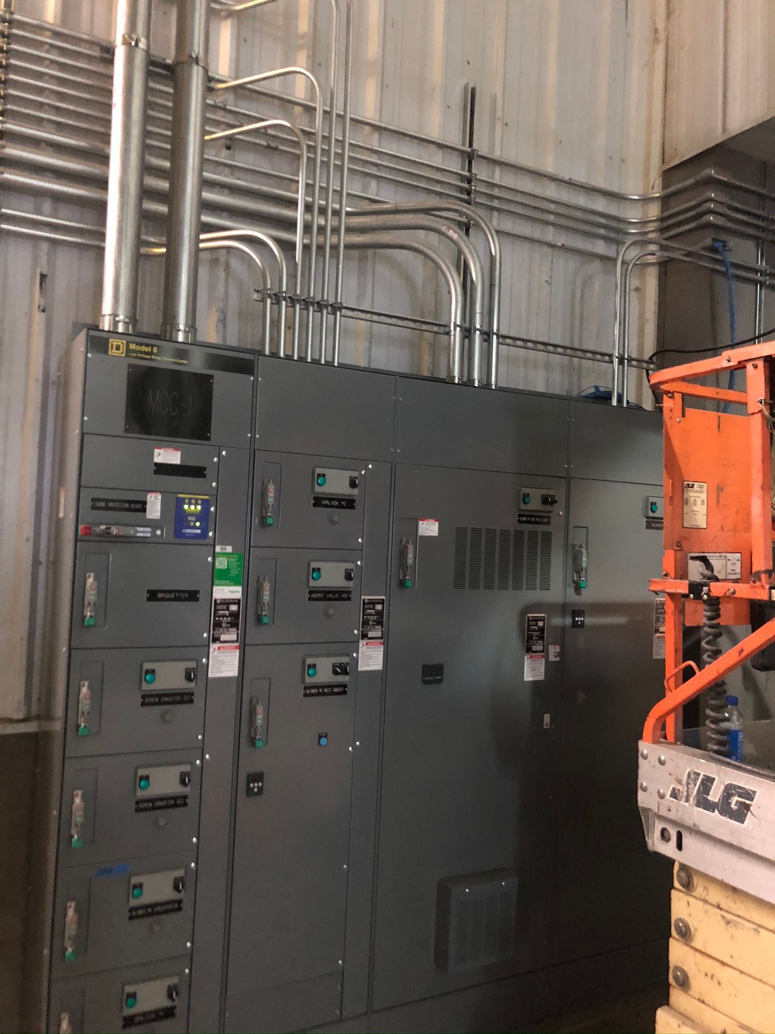 A large electrical panel in a building with a crane in the background.