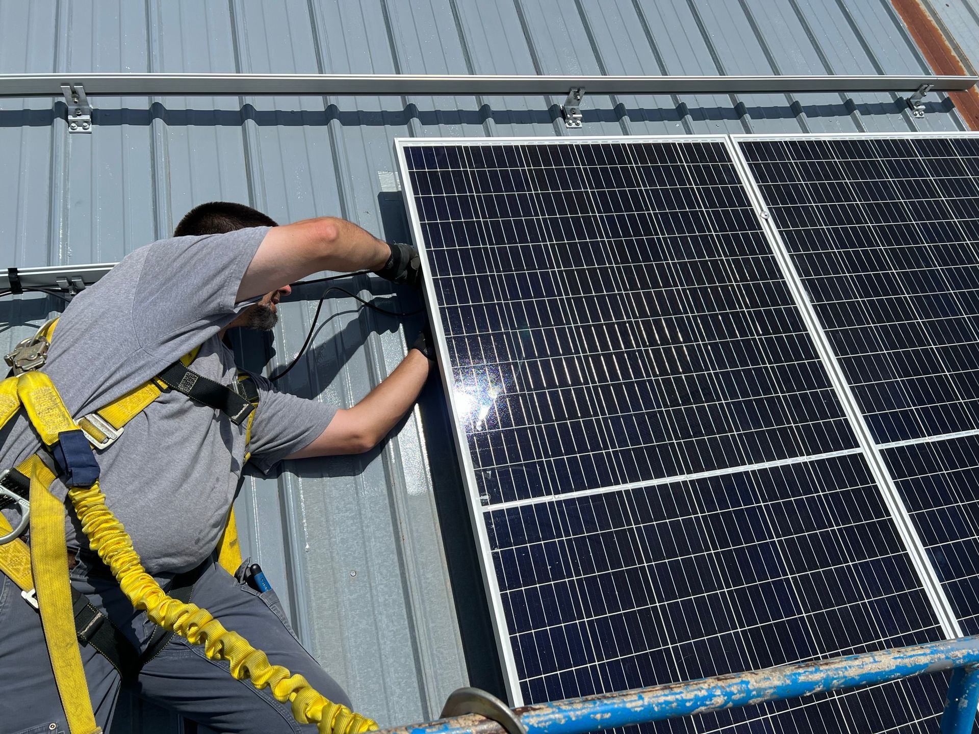 A man is installing solar panels on the roof of a building