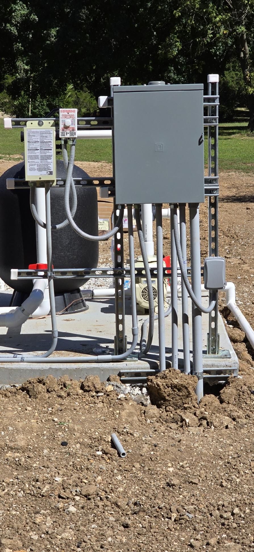 A large electrical box is sitting in the middle of a dirt field.