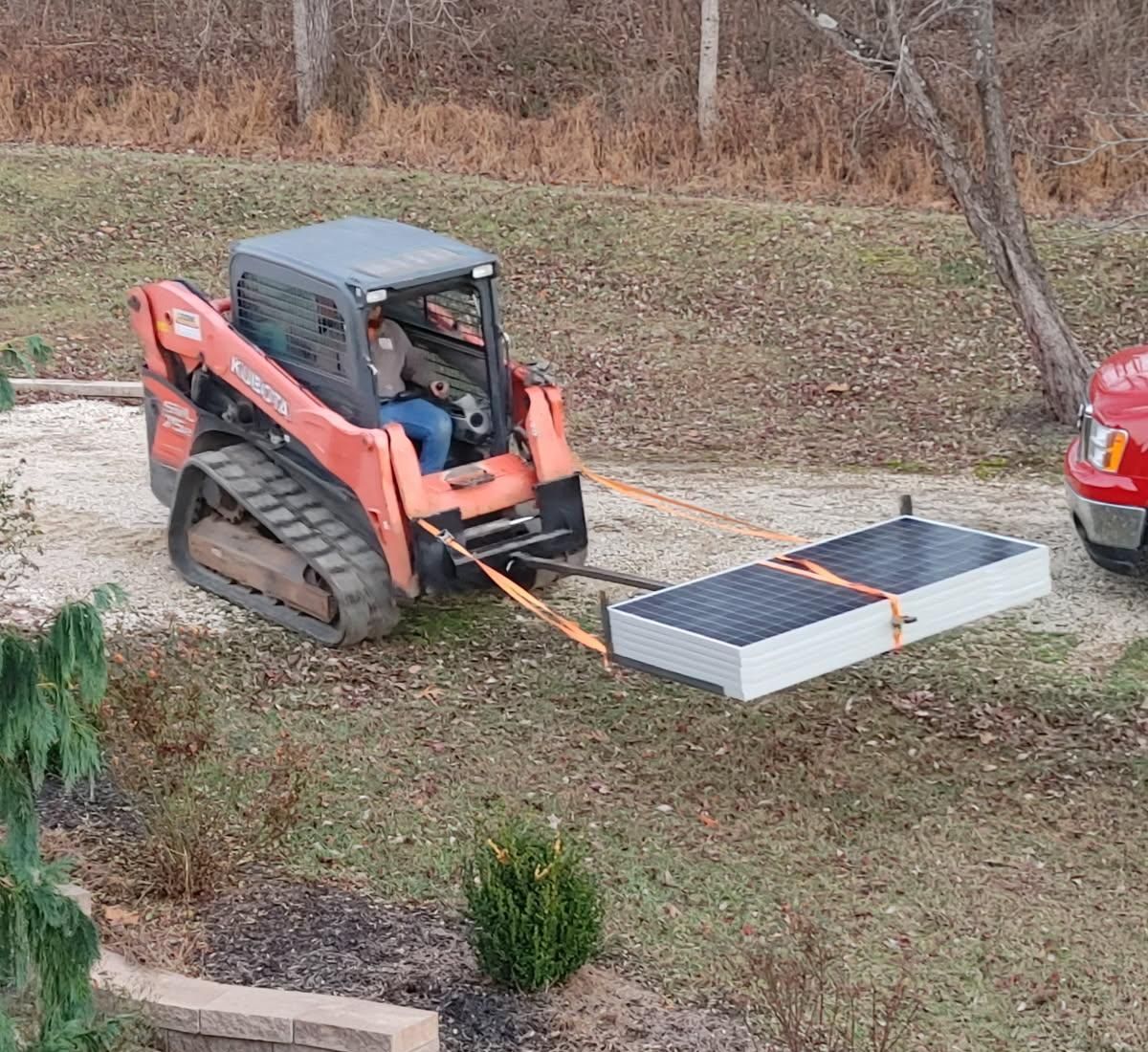 A man is driving a bulldozer with a solar panel attached to it.