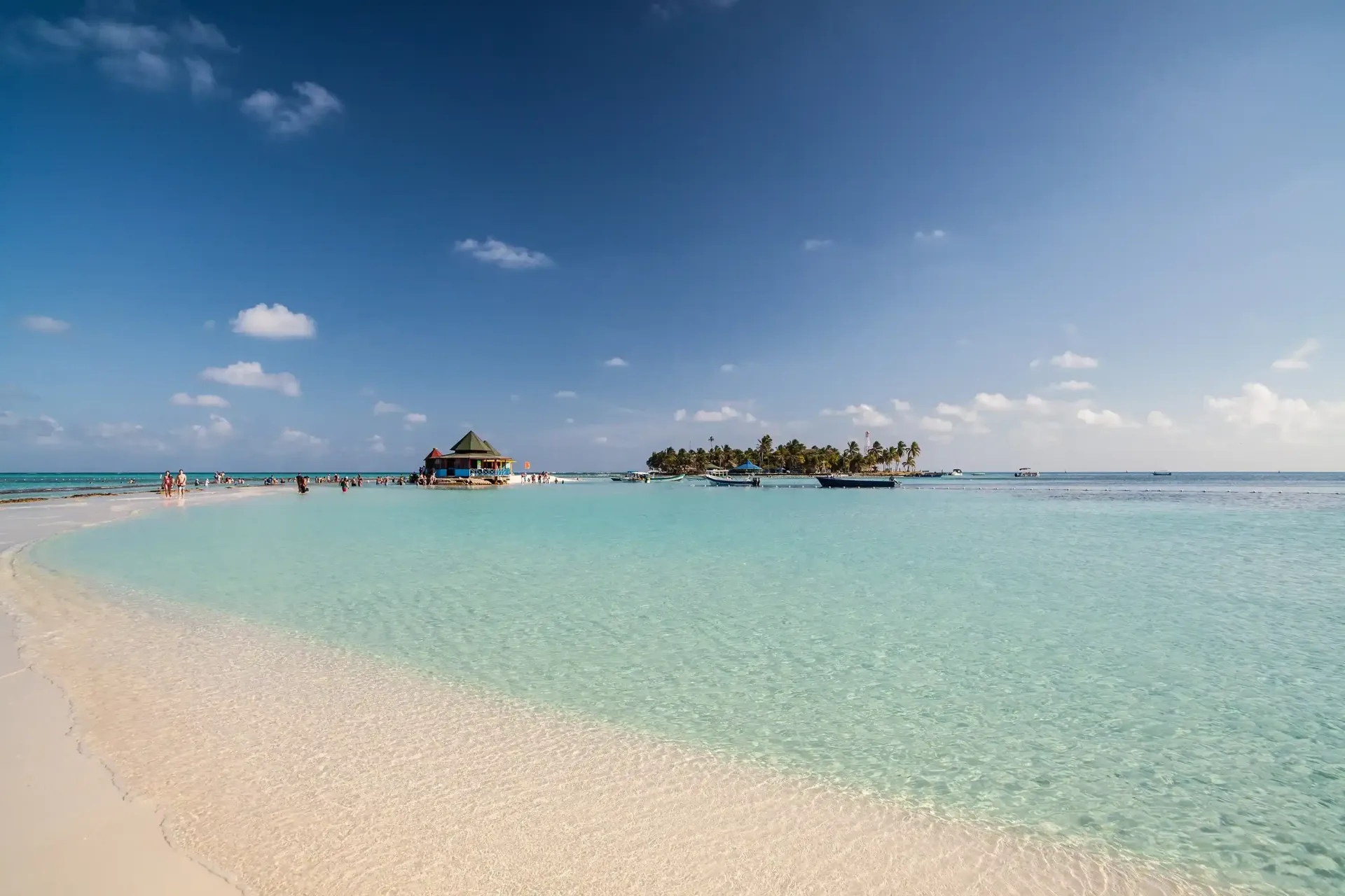 Banca de arena y mar poco profundo en playas de San Andrés; zona de baño tranquila para viajar en familias y amigos.