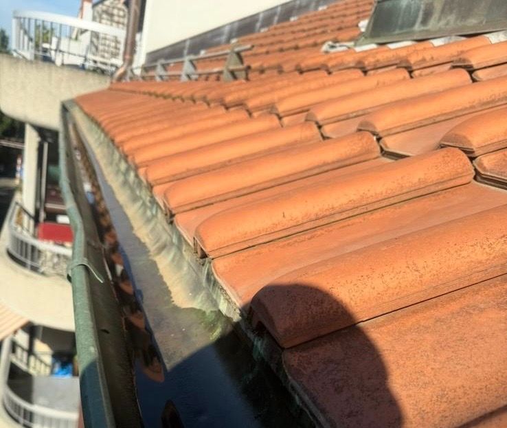 Eine Nahaufnahme eines Ziegeldachs mit einer Dachrinne.