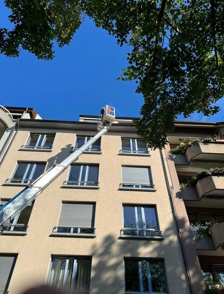 Ein Mann in einem Eimer arbeitet auf dem Dach eines Gebäudes.