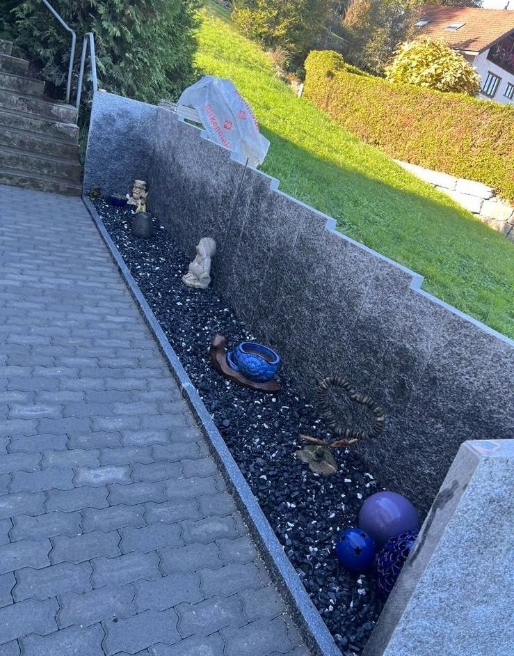 Ein gemauerter Gehweg mit einem Pflanzkübel voller Steine und Blumen