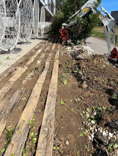 Eine Reihe Holzbretter liegt auf einem Erdhaufen.