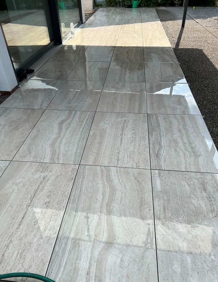 Eine Terrasse mit vielen Fliesen und einem grünen Schlauch.