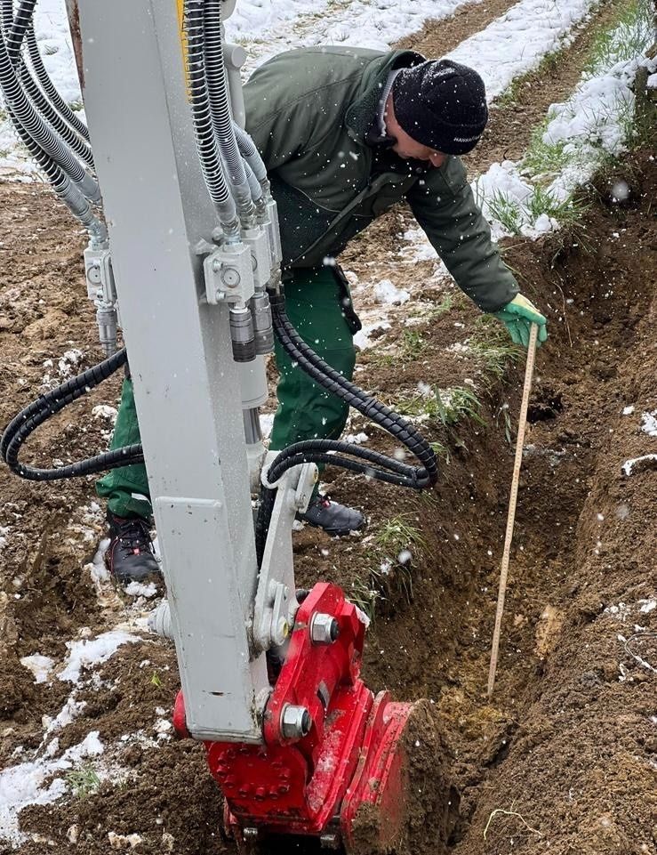 Ein Mann gräbt mit einem Bagger ein Loch in den Boden.