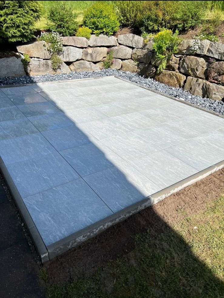 Eine Betonterrasse mit einer Steinmauer im Hintergrund.