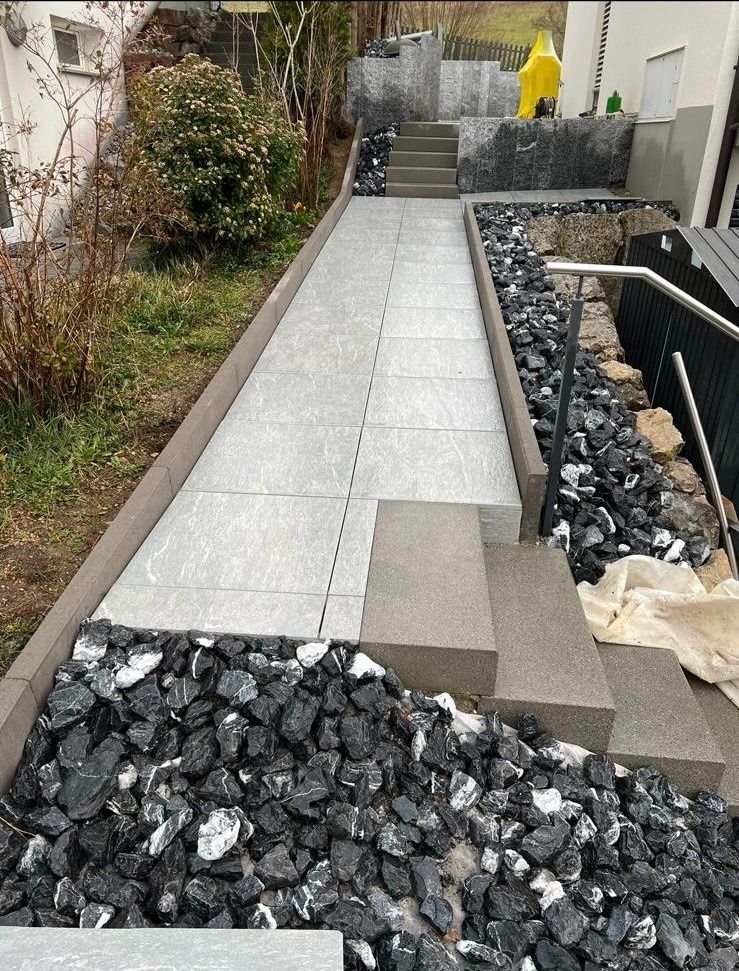 Ein Steinweg, umgeben von schwarzen Felsen und Treppen