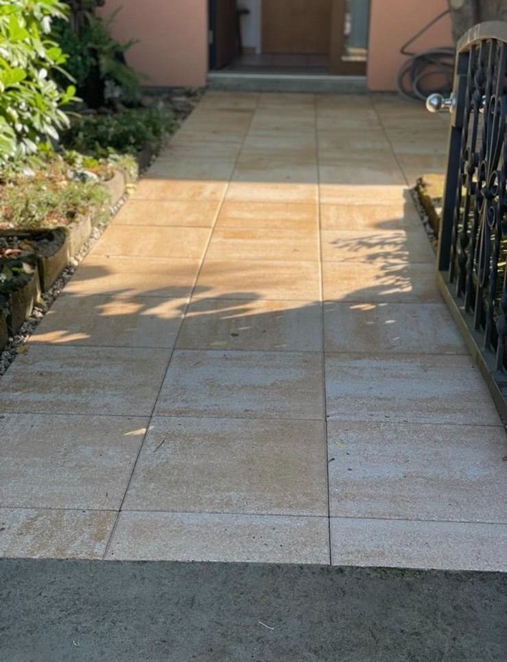 Ein gefliester Gehweg, der zu einem Haus mit einem Zaun führt