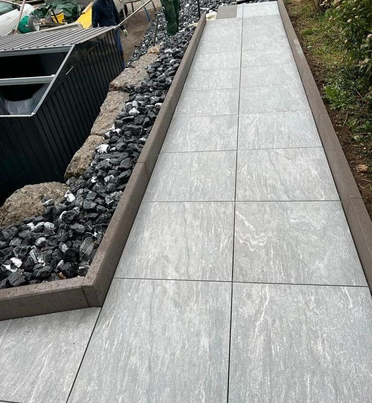 Ein Gehweg mit Fliesen und Steinen an der Seite