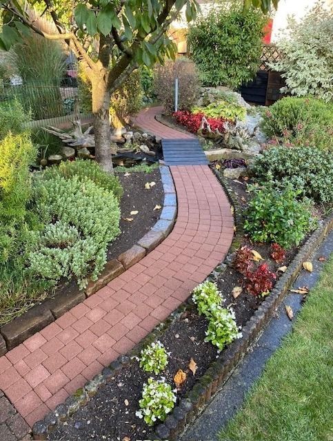 Ein gemauerter Gehweg in einem Garten, umgeben von Pflanzen und Bäumen