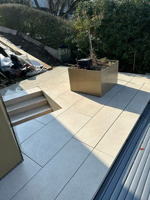 Auf einer Terrasse neben einer Treppe steht ein Blumentopf.