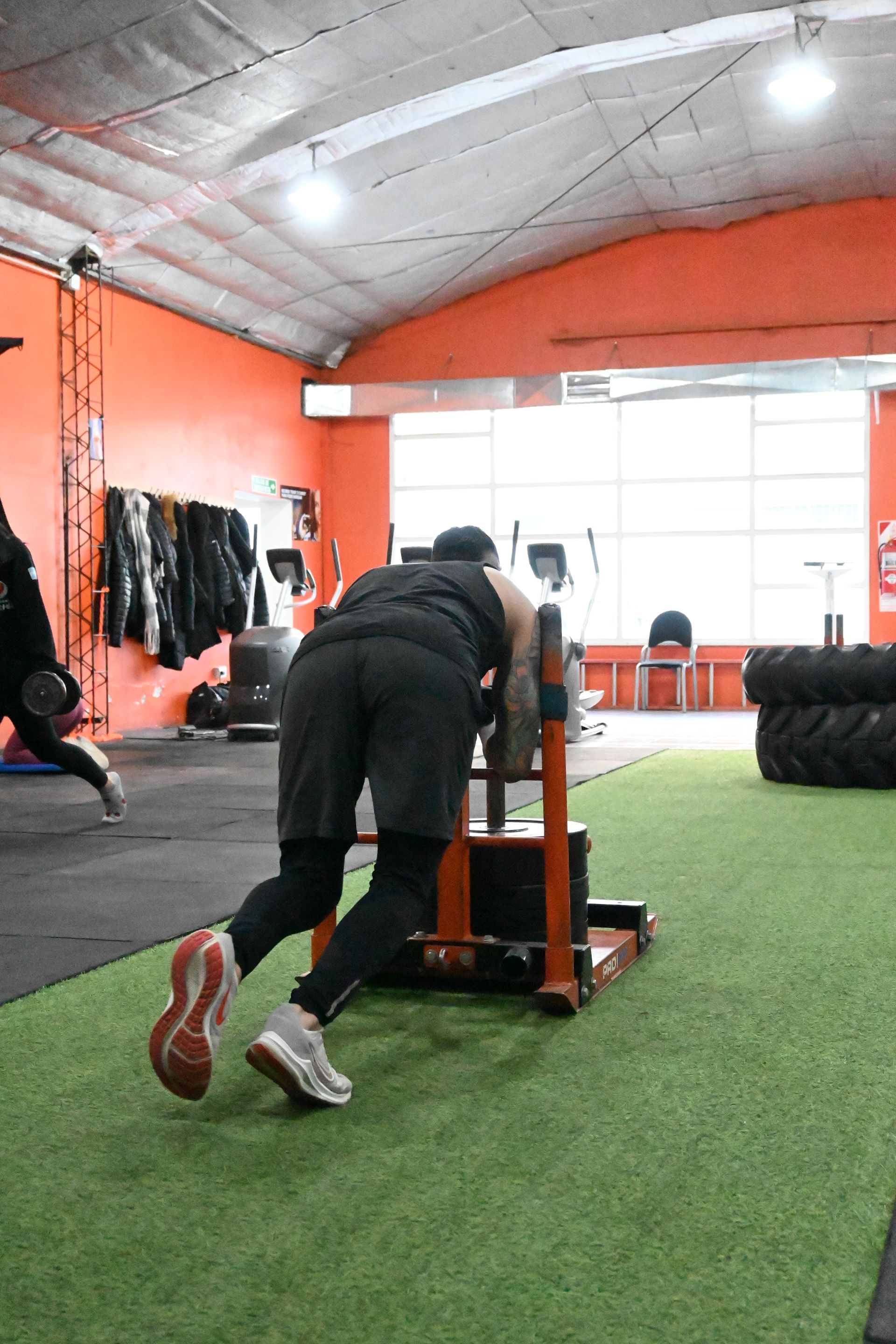 Un hombre está empujando un trineo en un gimnasio.