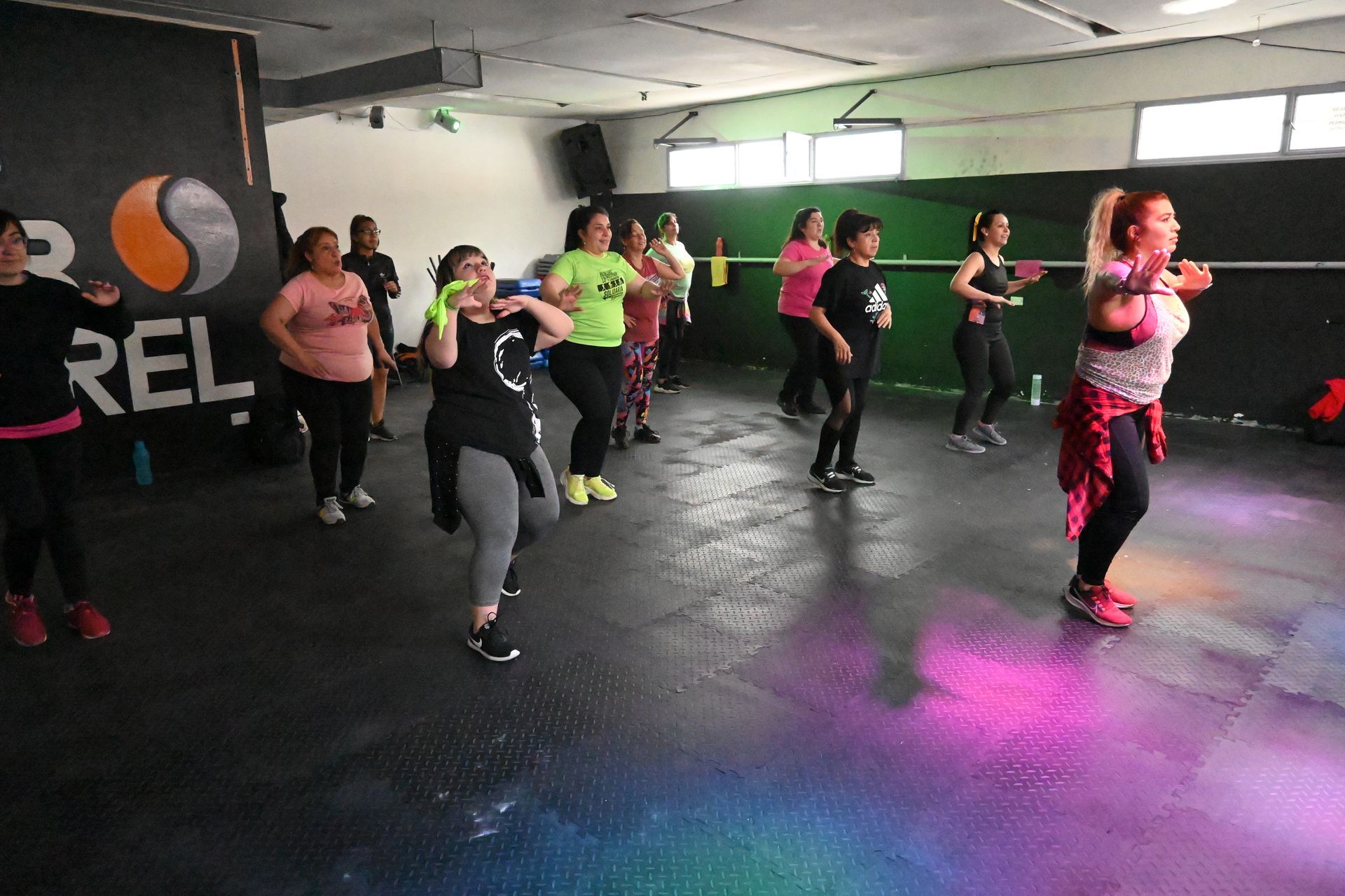 Un grupo de personas está bailando en un gimnasio.