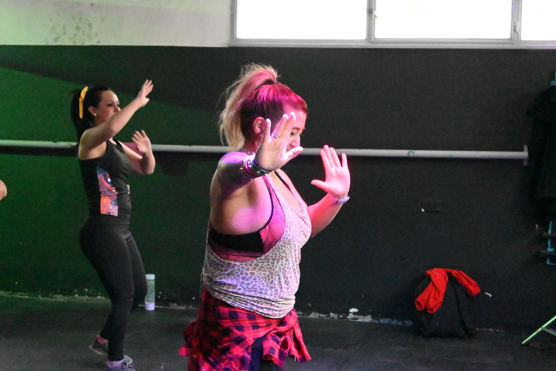 Dos mujeres bailan en una habitación con una pared verde.