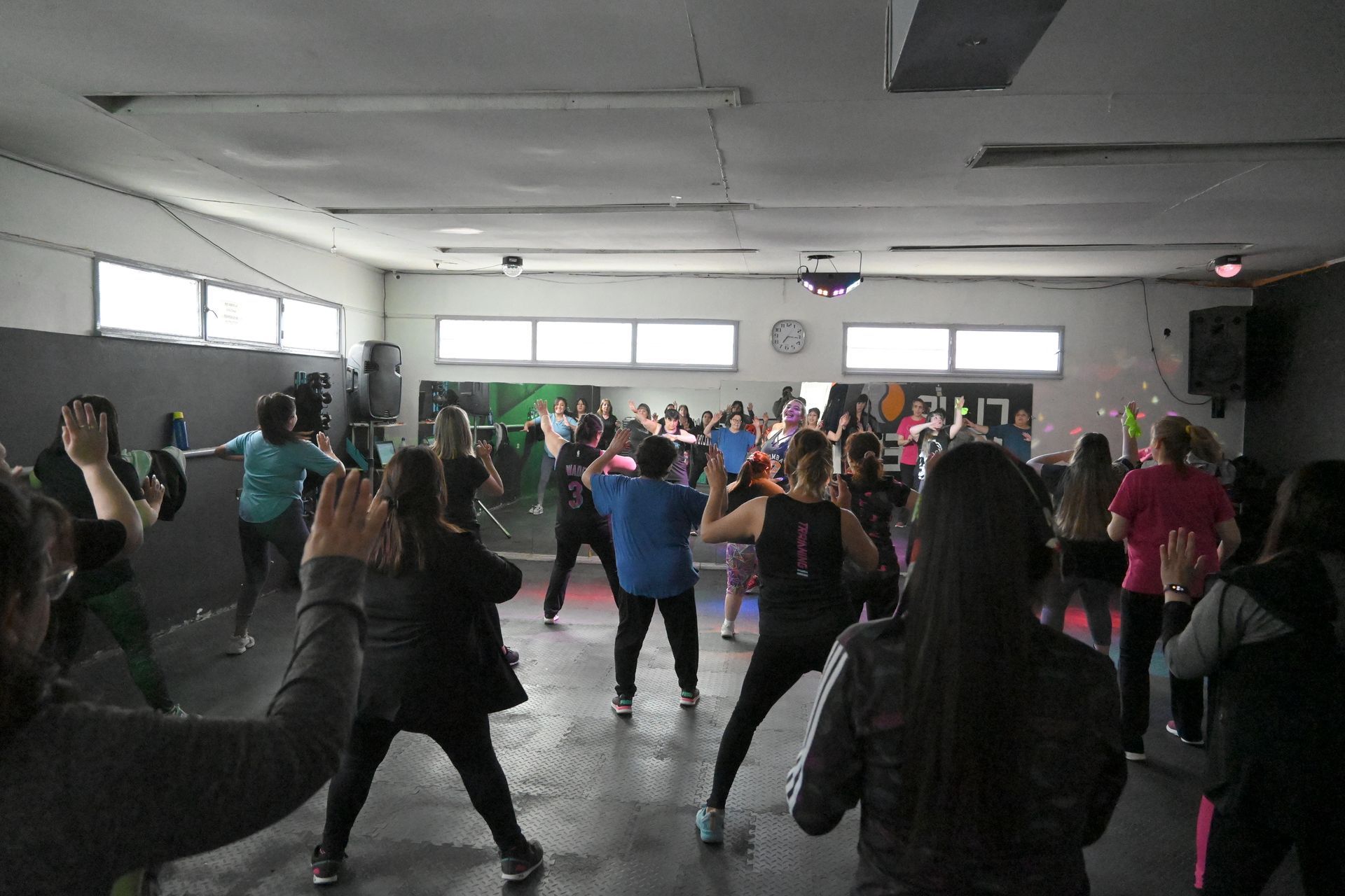 Un grupo de personas está bailando en un gimnasio.