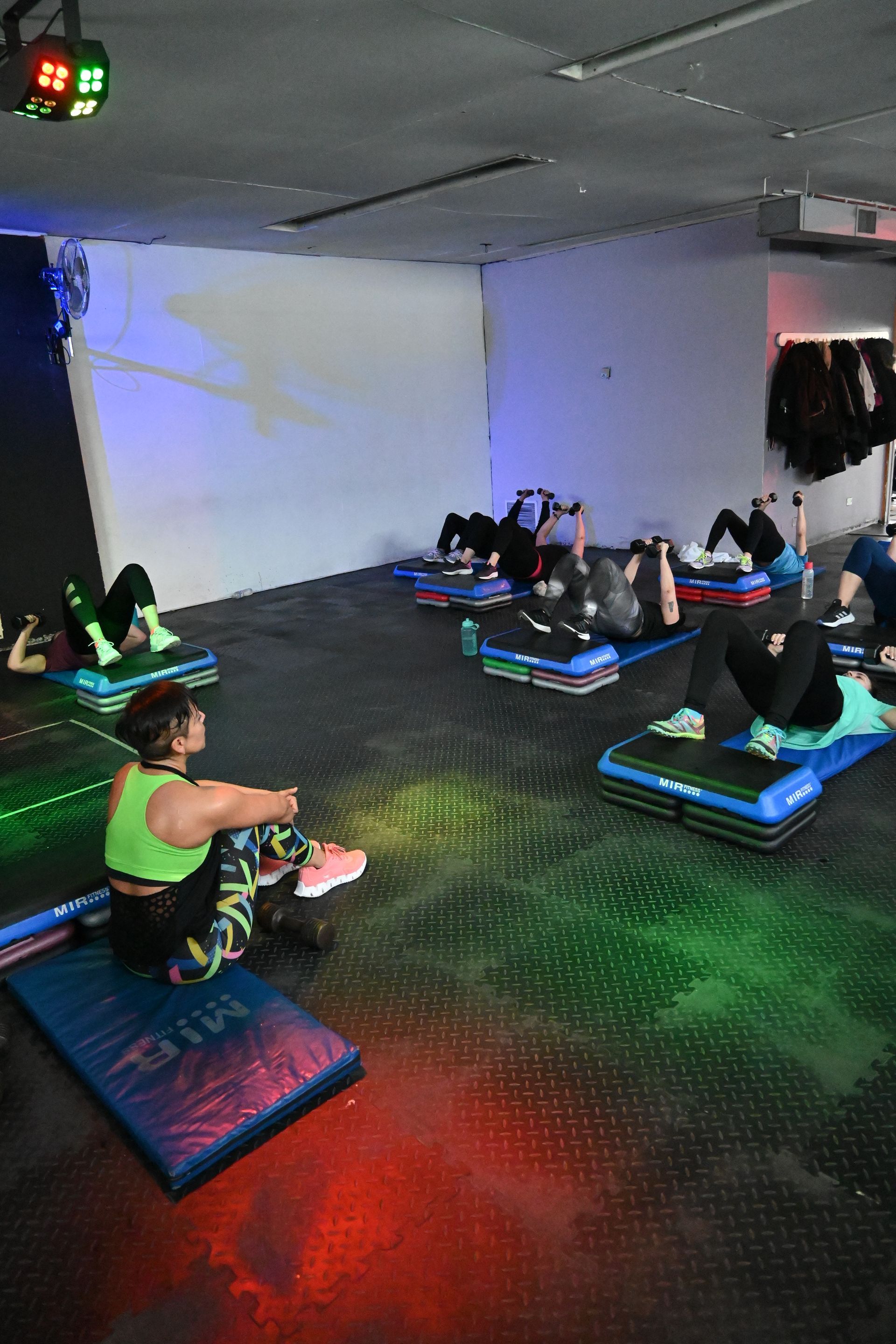 Un grupo de personas está haciendo ejercicios sobre colchonetas en un gimnasio.