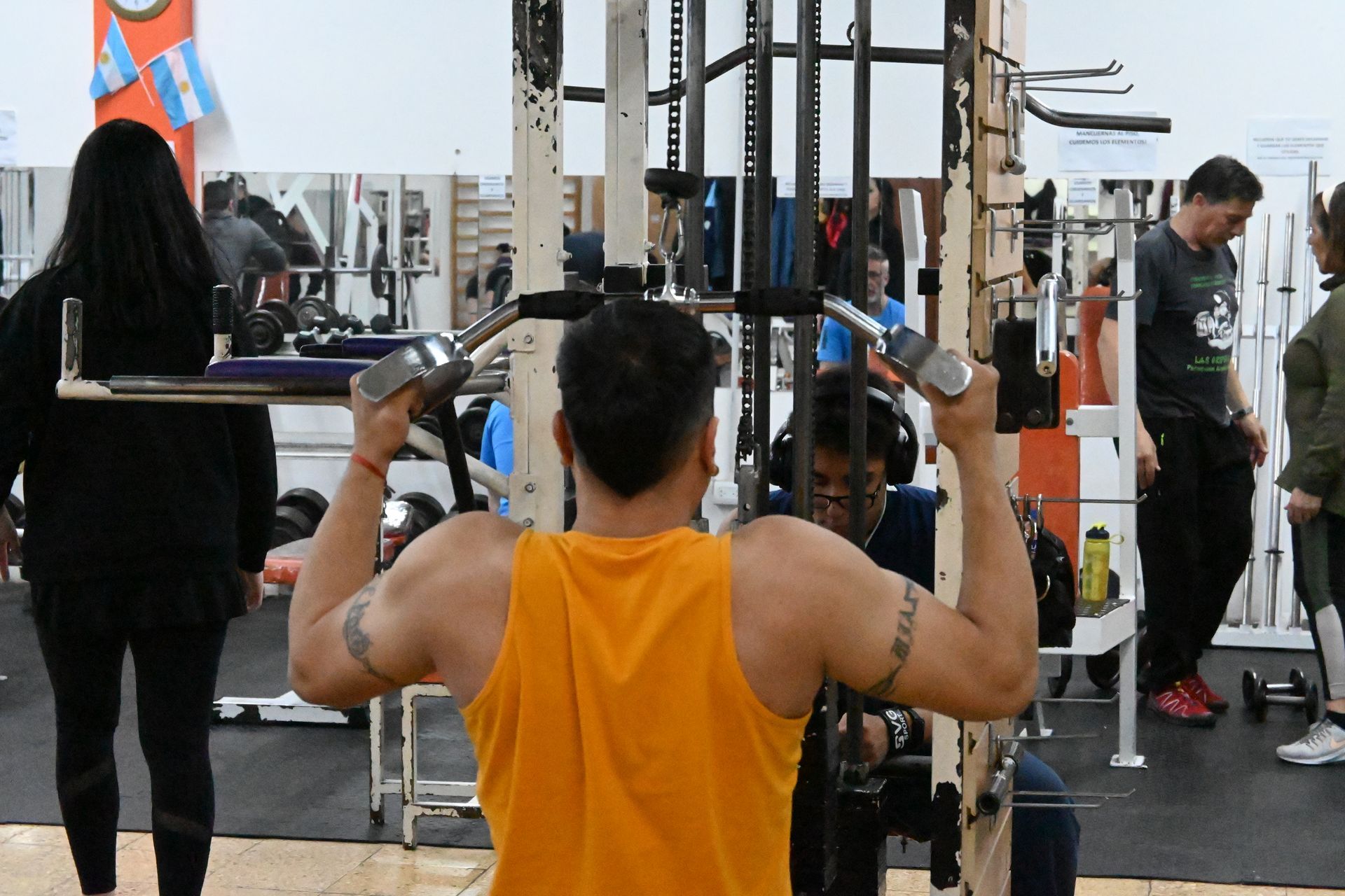 Un hombre con una camiseta amarilla está usando una máquina en un gimnasio.