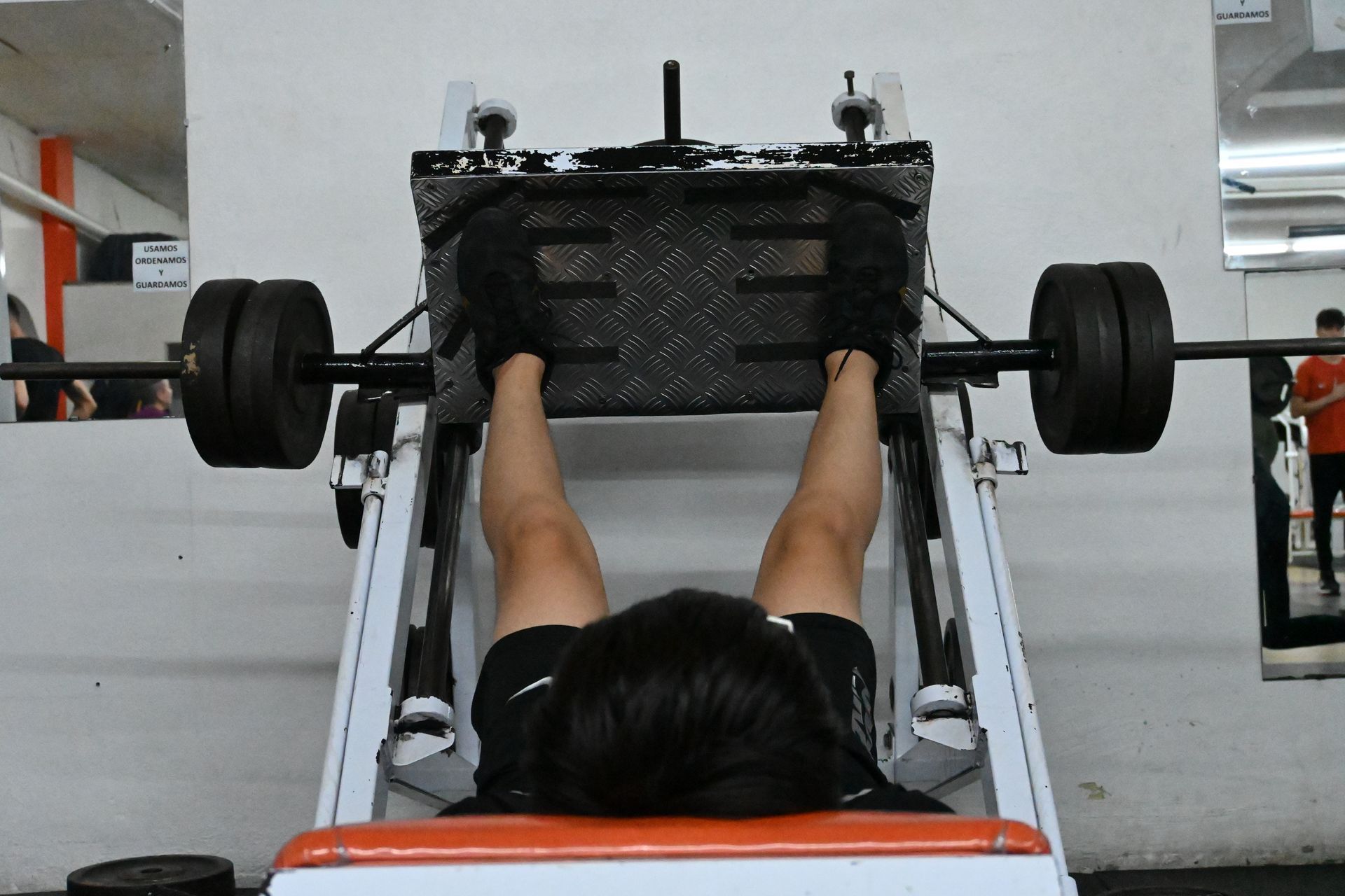 Un hombre está usando una máquina de prensa de piernas en un gimnasio.