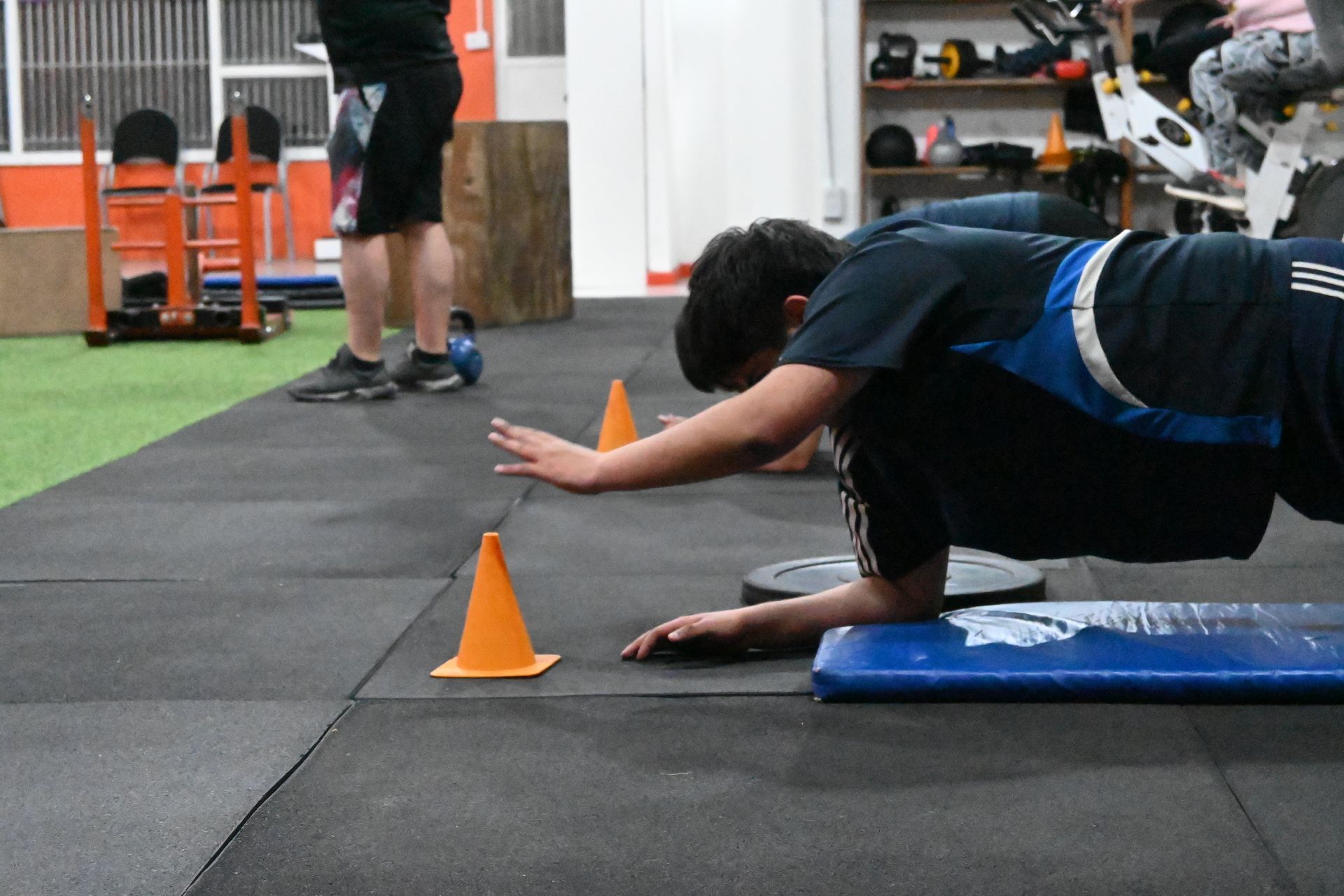 Un hombre está haciendo flexiones sobre una colchoneta en un gimnasio.