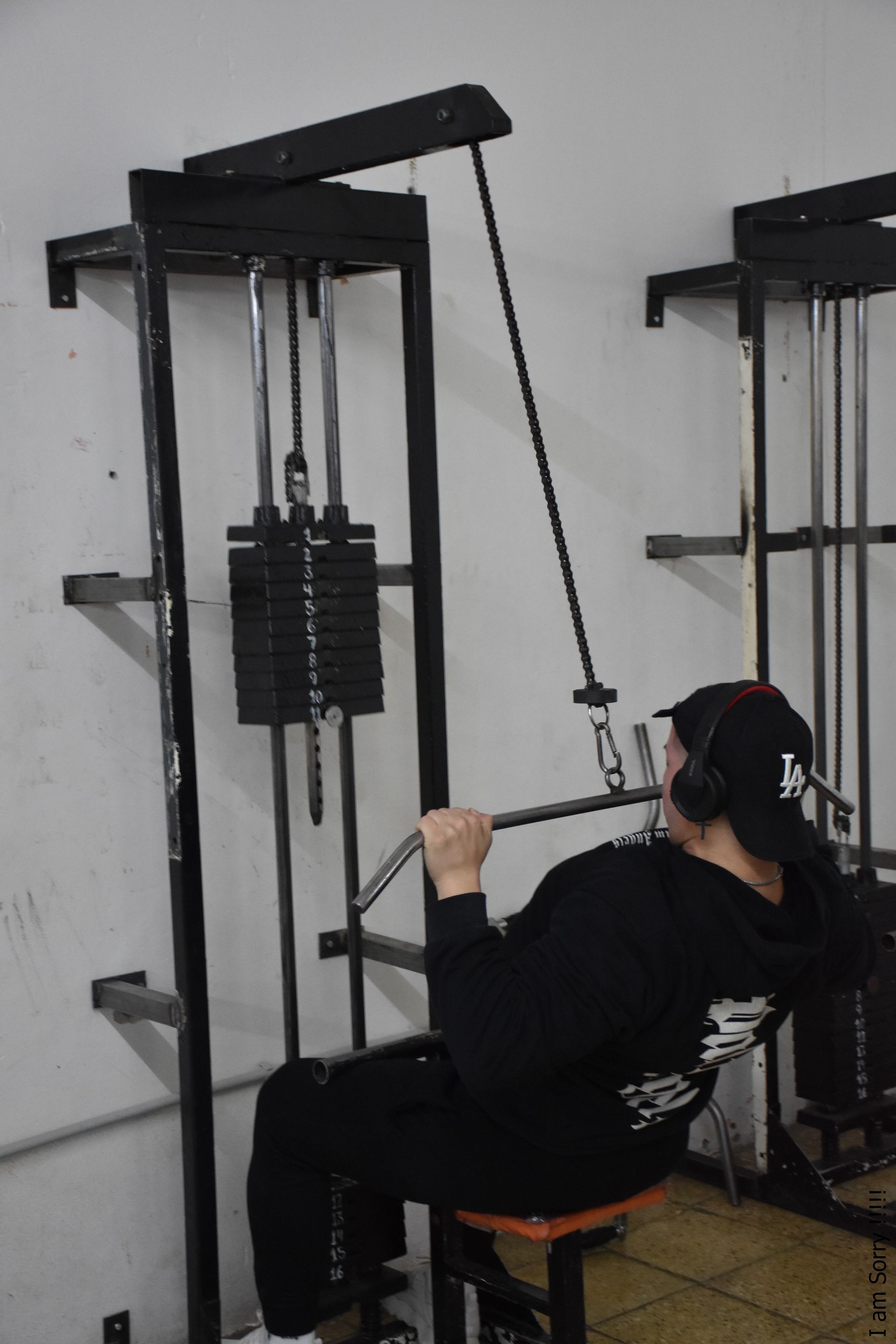 Un hombre está usando una máquina de dorsales en un gimnasio.