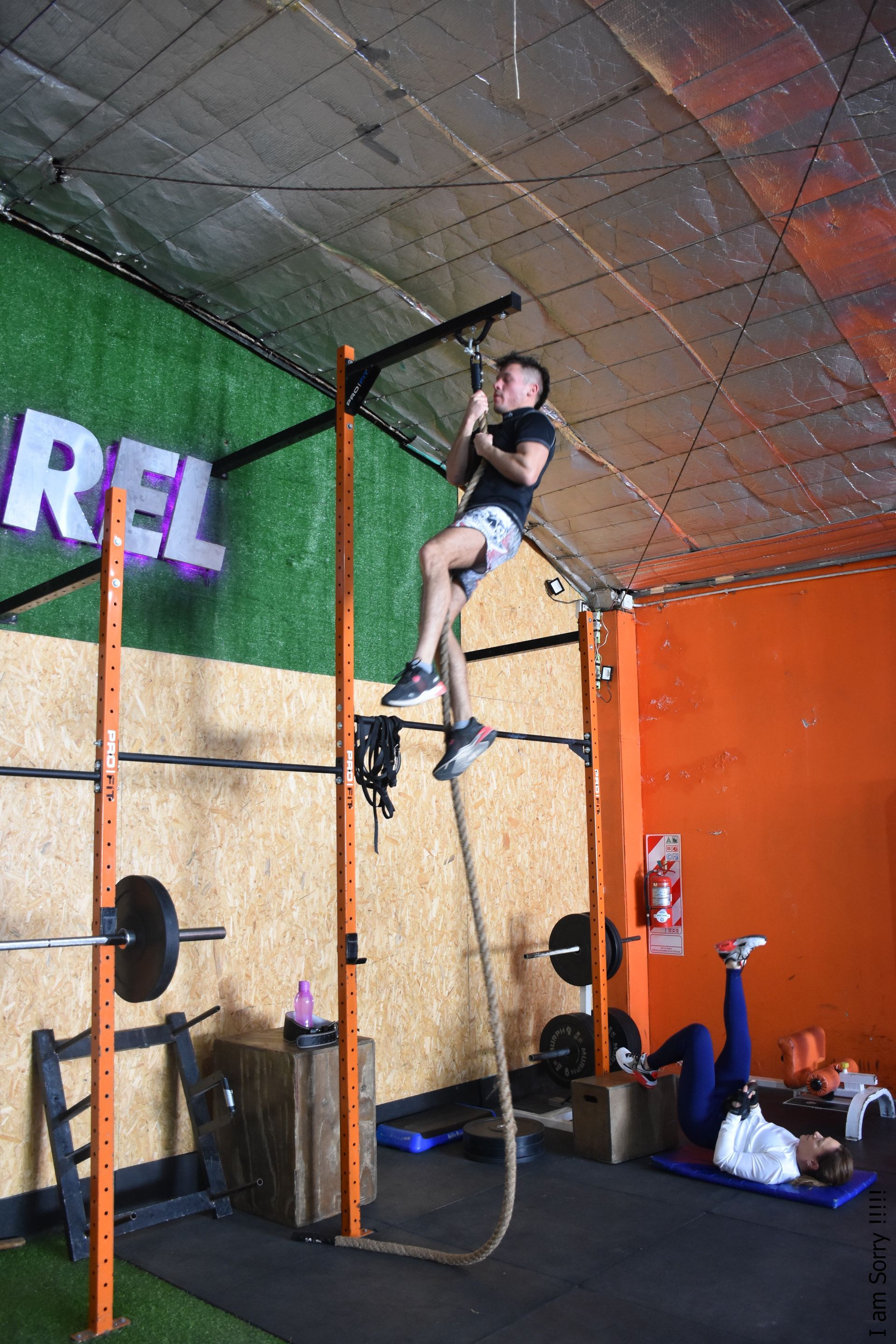 Un hombre está escalando una cuerda en un gimnasio.