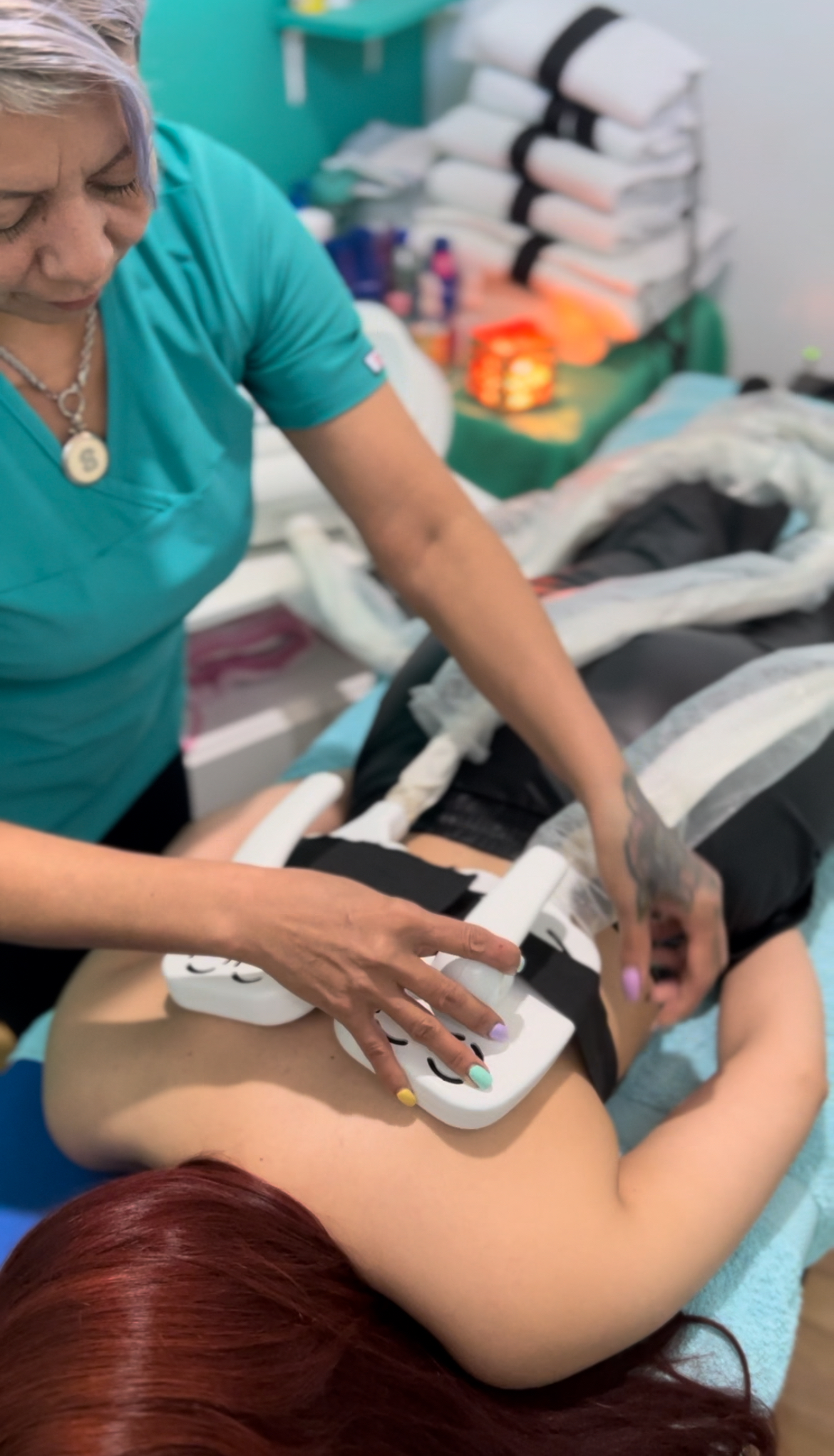 Una mujer está acostada en una cama recibiendo un tratamiento en la espalda.