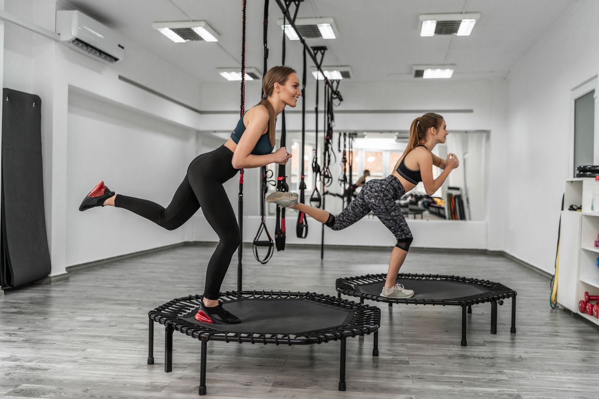 Dos mujeres están haciendo ejercicios en trampolines en un gimnasio.