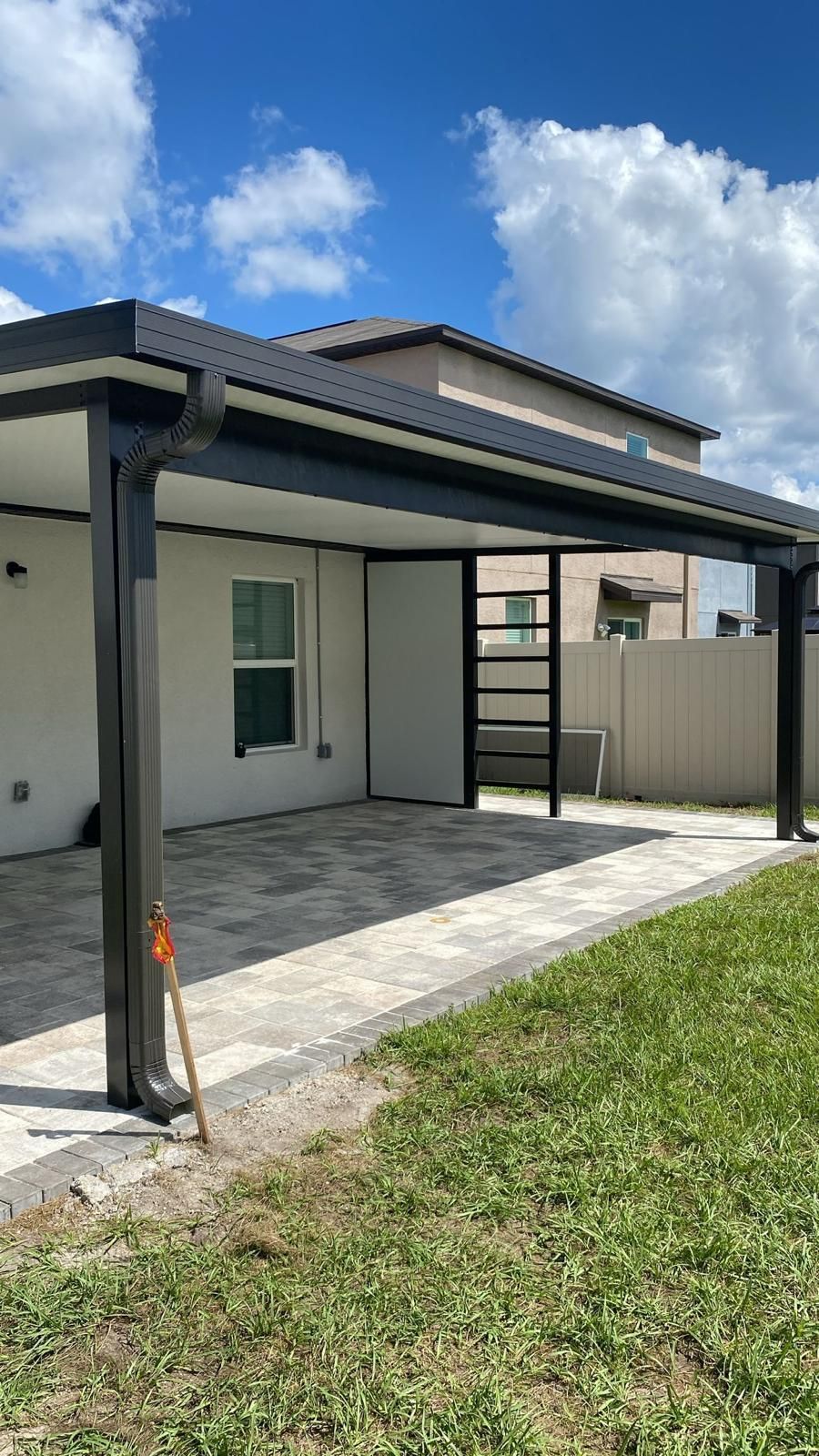 Screened patio with black frames, open doors, and a person using a blower. Outdoors, daytime.