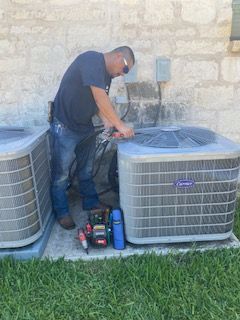 A man is working on an air conditioner outside of a house.