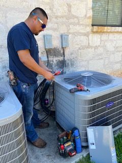 A man is working on an air conditioner outside of a house.