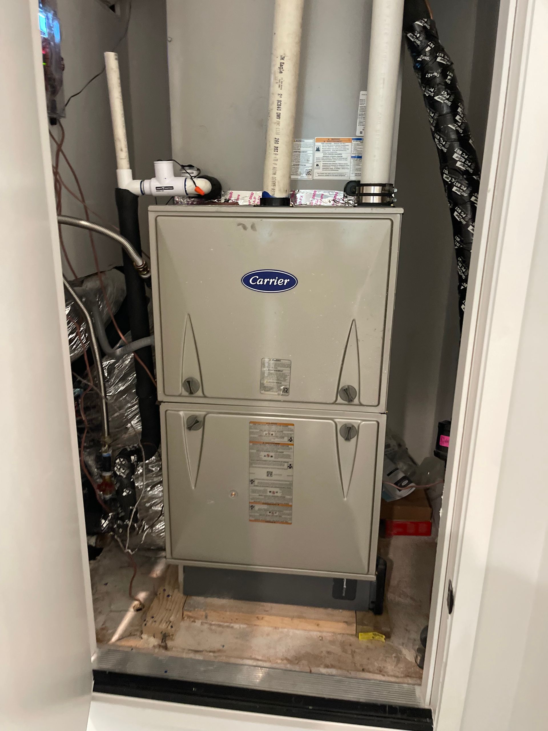 A furnace is sitting inside of a closet in a room.
